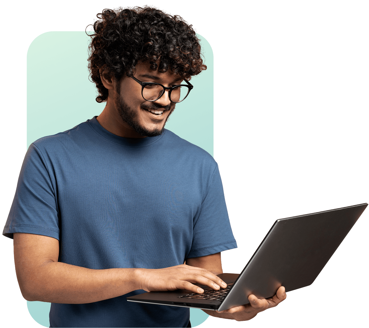 Retrato de um homem jovem com barba, cabelo grande cacheado e óculos, vestindo camisa azul, sorrindo confiantemente enquanto segura um laptop cinza contra um fundo claro e verde.